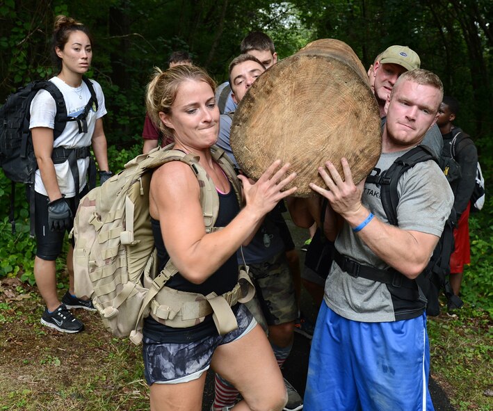 Maj. Katherine Stowe, JSTARS Recap Division program manager, and Airman Samuel Pryor, C3I and Networks Directorate administration specialist, and others hoist a log onto their shoulders as part of the Team Cohesion Challenge during a GORUCK program on base Aug. 24. More than 40 Airmen were divided into three teams during the team event. (U.S. Air Force photo by Jerry Saslav)