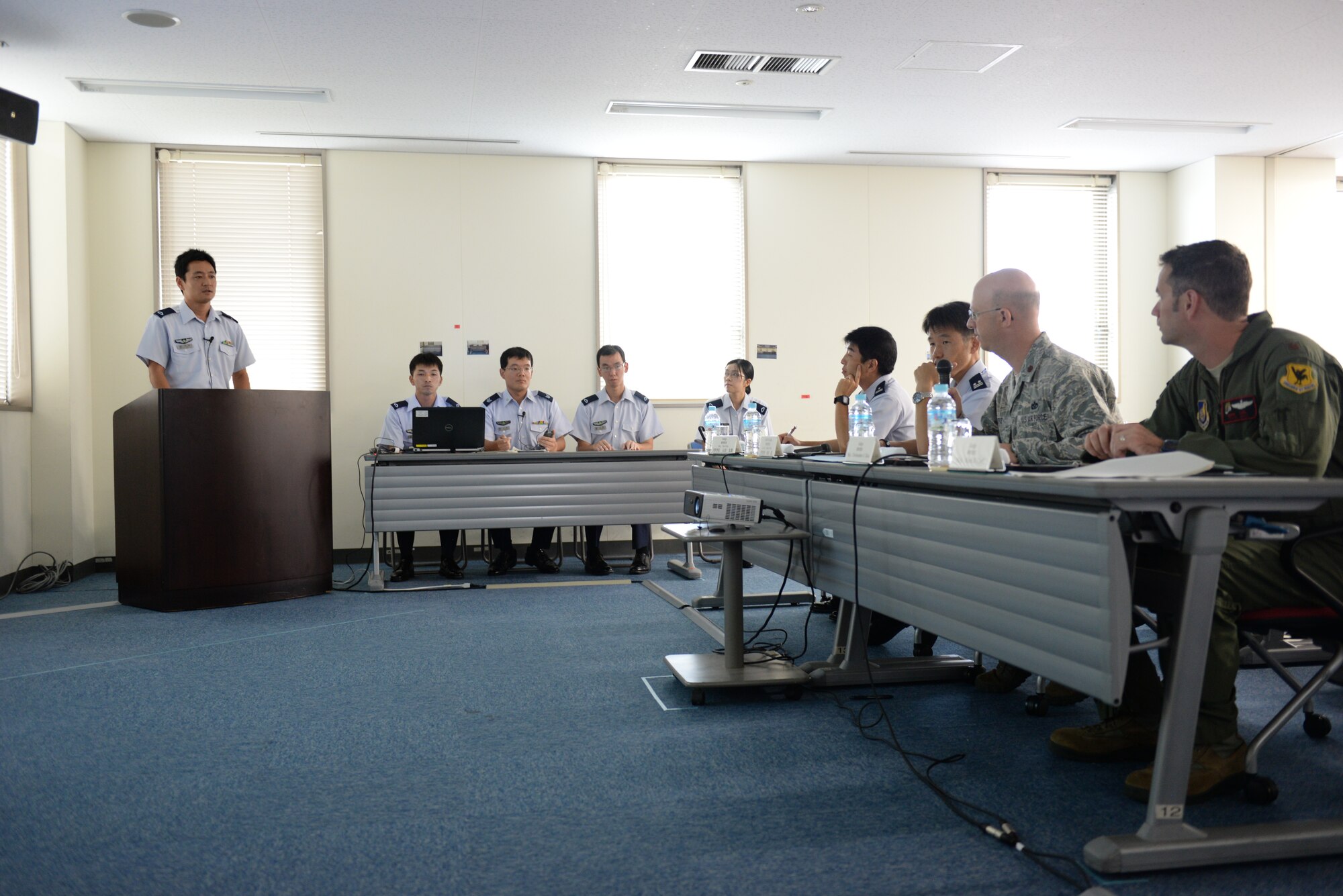 United States Air Force Maj. Christopher L. Teke, 18th Civil Engineer Squadron officer, and Maj. Mark Carl, 909th Air Refueling Squadron assistant director of operations, listen to Airmen from Japan Air Self Defense Force give briefings in English during a completion at Naha Air Base, Japan, Aug. 26, 2015. JASDF hosted an English briefing contest to be judged by American Airmen. (U.S. Air Force photo by Senior Airman Omari Bernard)