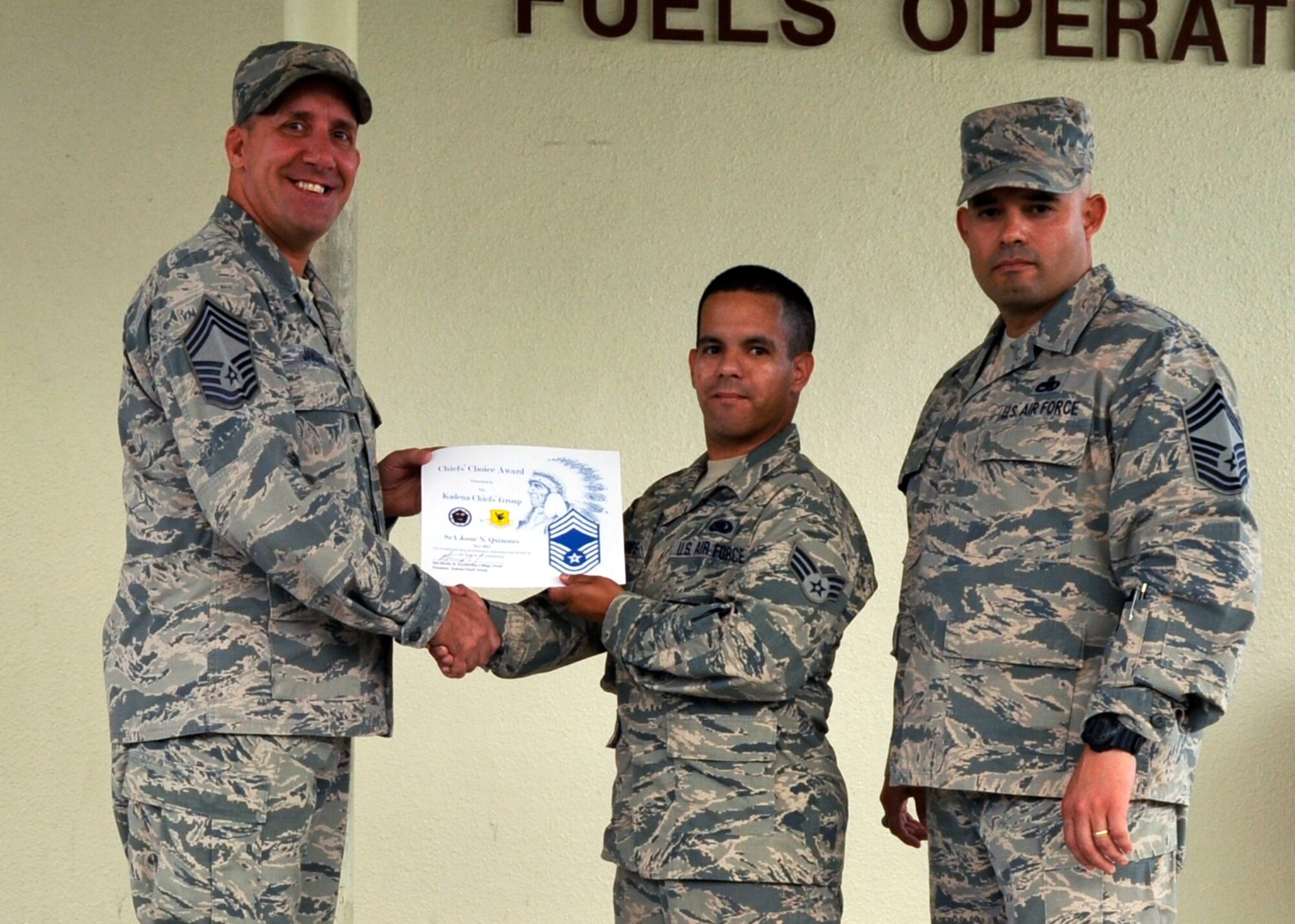 Chief Master Sgt. Daniel Janssen, 18th Logistics Readiness Squadron superintendent, and Chief Master Sgt. Jose Alvarez Jr., 18th Component Maintenance Squadron superintendent, presents Senior Airman Josque N. Quinones, a petroleum, oils and lubricants journeyman with the 18th LRS, with a certificate for the Chief’s Choice Award on Kadena Air Base, Japan, Aug. 27, 2015. Recipients of the Chiefs Choice Award are nominated for outstanding professionalism, customs, courtesies, bearing and civic contributions to Kadena and the local community. (U.S. Air Force photo by Airman 1st Class Nicholas Emerick)