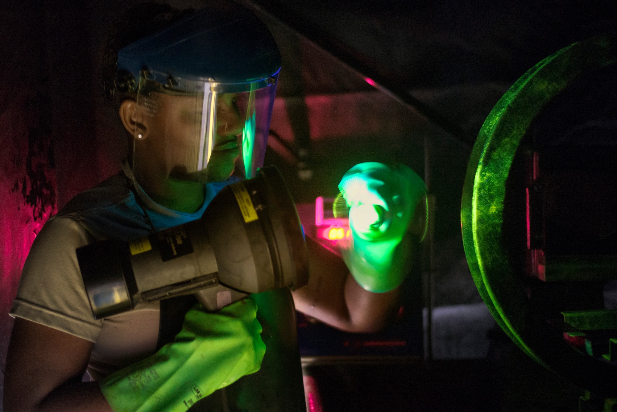 Senior Airman Kayla Hayes, 374th Maintenance Squadron nondestructive inspection technician, inspects an aircraft part during a magnetic particle test, Aug. 26, 2015, at Yokota Air Base, Japan. A magnetic particle solution is used to fill any cracks in a suspected damaged piece of equipment which well then glow under a black light to determine whether it's damaged. (U.S. Air Force photo by Airman 1st Class Delano Scott/Released)