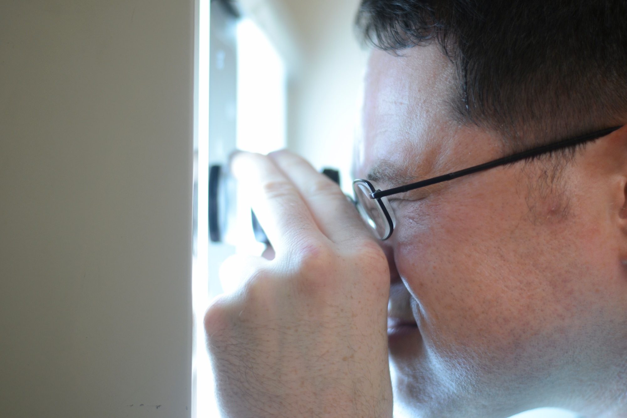 Staff Sgt. Eric Noah, 374th Maintenance Squadron nondestructive inspection craftsman, views an x-ray image through a lens, Aug. 25, 2015, at Yokota Air Base, Japan. Nondestructive inspection Airmen interpret and evaluates aircraft and equipment defects not visible to the naked eye without dismantling the entire component. (U.S. Air Force photo by Airman 1st Class Delano Scott/Released)