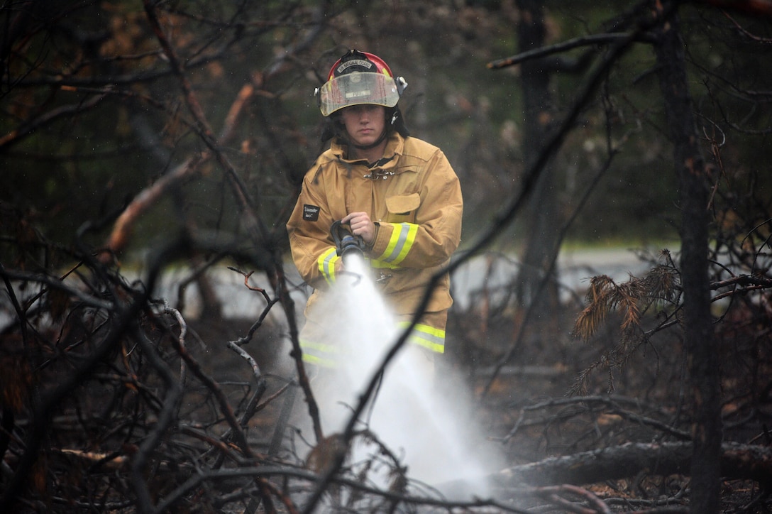 Senior Airman Brandon L. Ehlers, a firefighter with the 106th Rescue Wing, sprays down a burned area of woods Aug. 21, 2015, in Westhampton Beach, N.Y. Multiple agencies and fire departments responded to a major brush fire in the area. Firefighters from the 106th RQW checked for hot spots, which was a serious concern due to the dry weather during the previous week. (New York Air National Guard photo/Staff Sgt. Christopher S. Muncy)