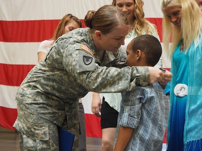 New York Army National Guard Staff Sgt. Marlana Watson presents her New York State Medal for Valor, the state's highest military honor, to her son Lassan Green, 6, Aug. 19, 2015.