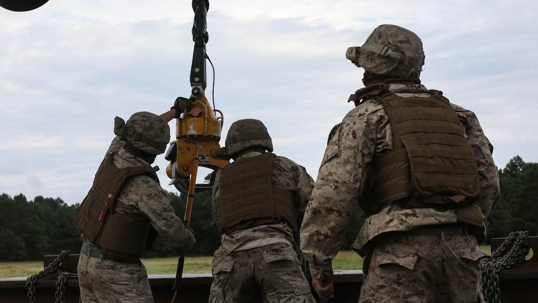 Marines with 2nd Transportation Support Battalion attach an 8,500-pound high beam to a pintle hook beneath a CH-53E Super Stallion during an external lift exercise at Marine Corps Base Camp Lejeune, N.C., Aug. 25, 2015. As the CH-53E hovered several yards above, on-the-ground Marines worked together to attach a beam weighing 8,500 pounds to the aircraft’s cable. 