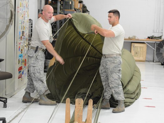 Tech. Sgt. Robert Ewings and Senior Airman Dan Meskell, Air Transportation Specialists assigned to 103rd Airlift Wing, Bradley Air National Guard Base, Connecticut, pack a parachute canopy during the C-130 Roundup here, August 24. The Round-Up is a friendly skills competition for aircrew members and aerial porters, with events in cargo loading and unloading, aerial cargo drops, combat landings and formation flying. (U.S. Air Force photo/Staff Sgt. Rachel Kocin)