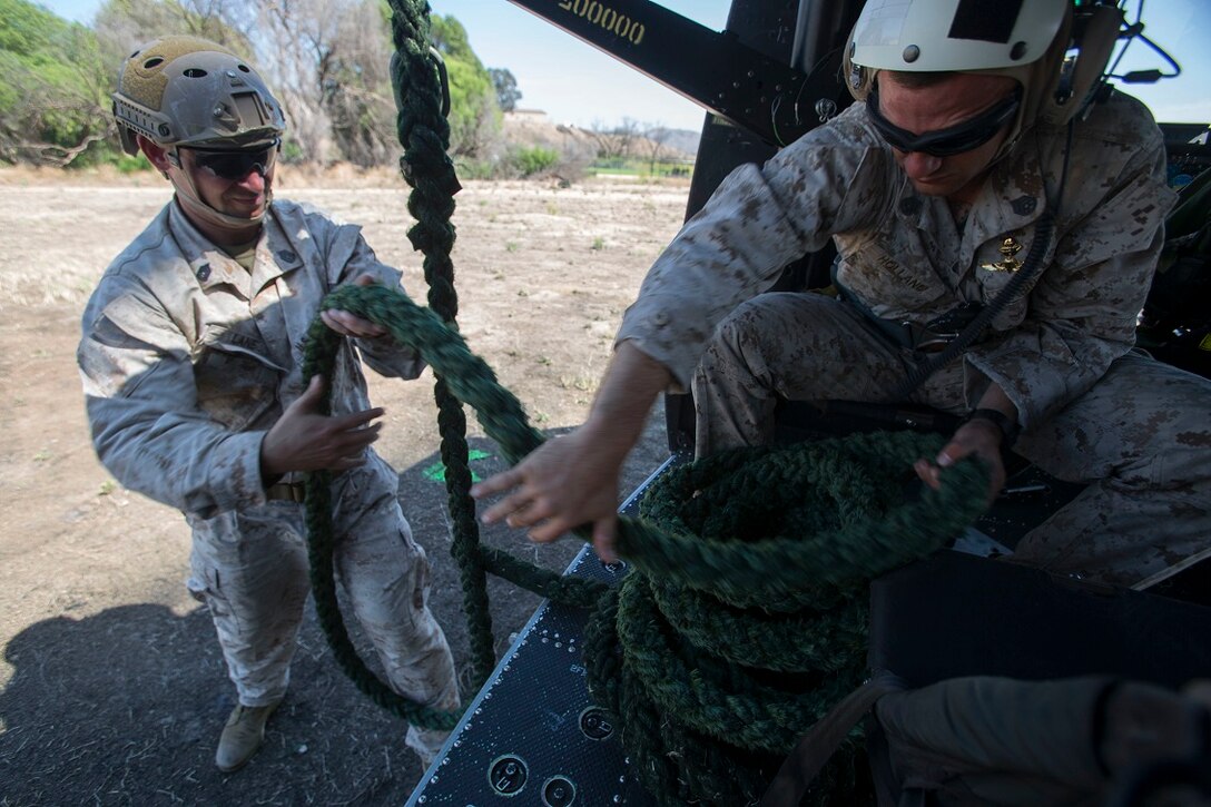 Staff Sgt. Steve Holland, a team leader, and Gunnery Sgt. Brett Lane, the platoon sergeant for Company A, 1st Reconnaissance Battalion, 1st Marine Division, I Marine Expeditionary Force, prepare equipment for a fast-roping exercise aboard Marine Corps Base Camp Pendleton, Calif., Aug. 18, 2015. The exercise was conducted with UH-1Y Huey helicopters operated by Marines with Medium Light Attack Helicopter Squadron 369, Marine Aircraft Group 39, 3rd Marine Aircraft Wing, I MEF. The cooperation of air and ground elements gives Marines access to obstructed locations and prepares them to face any challenge, anywhere. (U.S. Marine Corps photo by Lance Cpl. Caitlin Bevel)