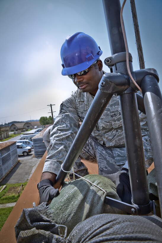 Tech. Sgt. Olandre L. Edwards, 644th Combat Communications Squadron radio frequency transmissions supervisor, adjusts sand bags on an antenna stand as part of a preventative-maintenance inspection to ensure reliable radio communications are maintained. The 644th CBCS is in place at Suwon Air Base, Japan, from Anderson Air Force Base, Guam, to help set up and maintain temporary communications. (U.S. Air Force photo by Tech. Sgt. Travis Edwards-Released/Released)