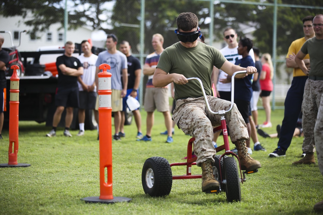 MARINE CORPS BASE HAWAII — Cpl. Jonah Tappangorgita, a cyber security specialist with the Communications & Information Systems Directorate and Albany, Ore., native, races through cones on a tricycle while wearing drunk goggles during the 101 Days of Summer Field Meet Unit Challenge held at Riseley Field aboard Marine Corps Base Hawaii, Aug. 21, 2015. Hosted by Marine Corps Community Services Hawaii, the field meet was composed of a combat obstacle course, jousting, truck tire flip race, tug of war, 880-meter relay race and big trike relay. The field meet was held to promote health and wellness within the MCB Hawaii community, as well build camaraderie between various units around the base. Service members could earn points in the 101 Days of Summer Program by participating in this event. Events such as this help support the mission of MCCS Hawaii, which is to contribute to the readiness and retention of Marines, Sailors and families aboard MCB Hawaii by providing fitness and recreation programs, as well as business activities in garrison and deployed environments. (U.S. Marine Corps photo by Lance Cpl. Harley Thomas/Released)