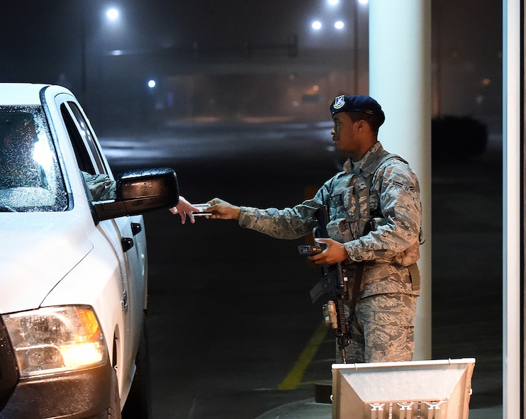 Airman 1st Class Bradley Hill, 90th Security Forces Squadron, checks the ID card of drivers at the front gate of F.E. Warren Air Force Base, Wyo., in the early-morning hours of April 8, 2015. Airmen work as entry controllers for 12-hour shifts starting the evening before at 6 p.m. (U.S. Air Force photo by R.J. Oriez)