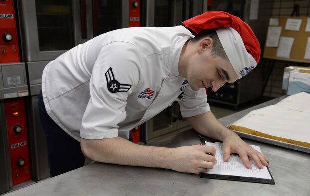 U.S. Air Force Airman 1st Class Jeremy P. Hnatiuk, a 354th Force Support Squadron shift leader, signs a food log in the kitchen of the Two Seasons Dining Facility, Aug. 27, 2015, at Eielson Air Force Base, Alaska. This paperwork tells Hnatiuk what he and other cooks need to prepare for each days meals. (U.S. Air Force photo by Airman 1st Class Cassandra Whitman/Released)