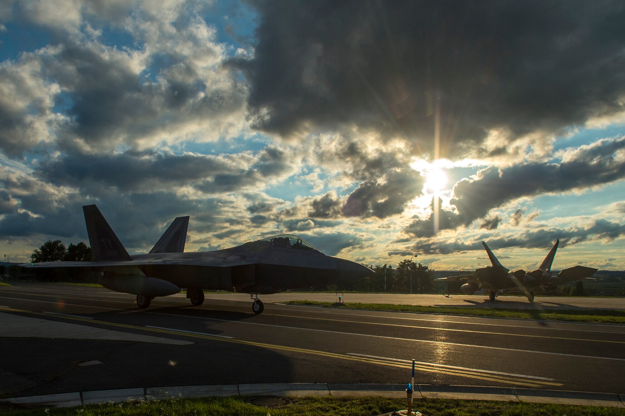 Two F-22 Raptor fighter aircraft assigned to the 95th Fighter Squadron at Tyndall Air Force Base, Fla., taxi to hardened aircraft shelters at Spangdahlem Air Base, Germany, Aug. 28, 2015.The U.S. Air Force deployed four F-22s, one C-17 Globemaster III and more than 50 Airmen to Spangdahlem in support of the first F-22 European training deployment. The inaugural F-22 training deployment to Europe is funded by the European Reassurance Initiative, a $1 billion pledge announced by President Obama in March 2014.(U.S. Air Force photo by Airman 1st Class Luke Kitterman/Released)