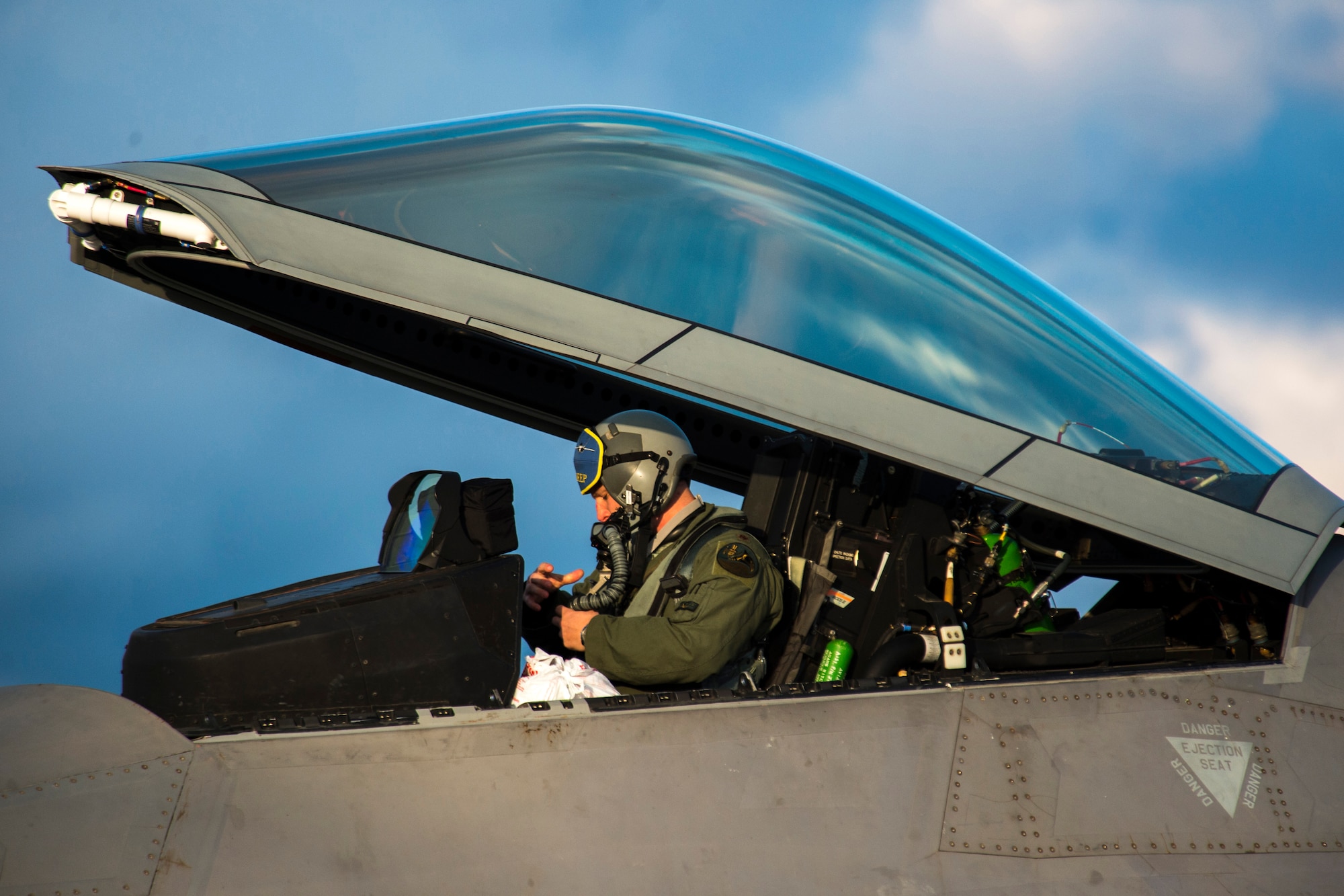 An F-22 Raptor fighter aircraft pilot assigned to the 95th Fighter Squadron at Tyndall Air Force Base, Fla., prepares to exit an F-22 at Spangdahlem Air Base, Germany, Aug. 28, 2015. The U.S. Air Force deployed four F-22 Raptors, one C-17 Globemaster III and more than 50 Airmen to Spangdahlem in support of the first F-22 European training deployment. The inaugural F-22 training deployment to Europe is funded by the European Reassurance Initiative, a $1 billion pledge announced by President Obama in March 2014.(U.S. Air Force photo by Airman 1st Class Luke Kitterman/Released)