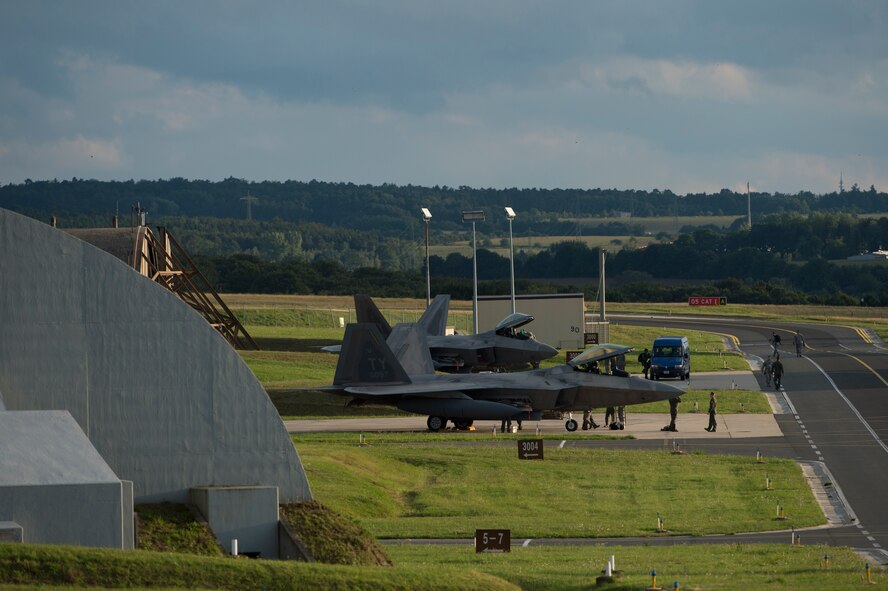 Members of the 95th Fighter Squadron from Tyndall Air Force Base, Fla., marshal two U.S. Air Force F-22 Raptor fighter aircraft near hardened aircraft shelters, Aug. 28, 2015, on Spangdahlem Air Base, Germany. The 95th FS deployed to Spangdahlem as part of the European Reassurance Initiative, which is intended to increase the capability, readiness and responsiveness of NATO forces in part by funding rotational force presence in Eastern Europe. This training deployment is also part of ensuring the 5th generation fighters can deploy to European bases and other NATO installations. (U.S. Air Force photo by Staff Sgt. Christopher Ruano/Released)