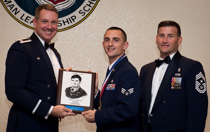 Col. Robert Lyman, Joint Base Charleston commander and Chief Master Sgt. Mark Bronson, 628th Air Base Wing command chief present the John L. Levitow Award to Senior Airman Patrick Esmerado, 628th Logistics Readiness Squadron supply technician Aug. 27, 2015, at the Charleston Club on JB Charleston, S.C. The John L. Levitow award is given for a student’s exemplary demonstration of excellence, both as a leader and a scholar. (U.S. Air Force photo/Airman 1st Class Clayton Cupit)