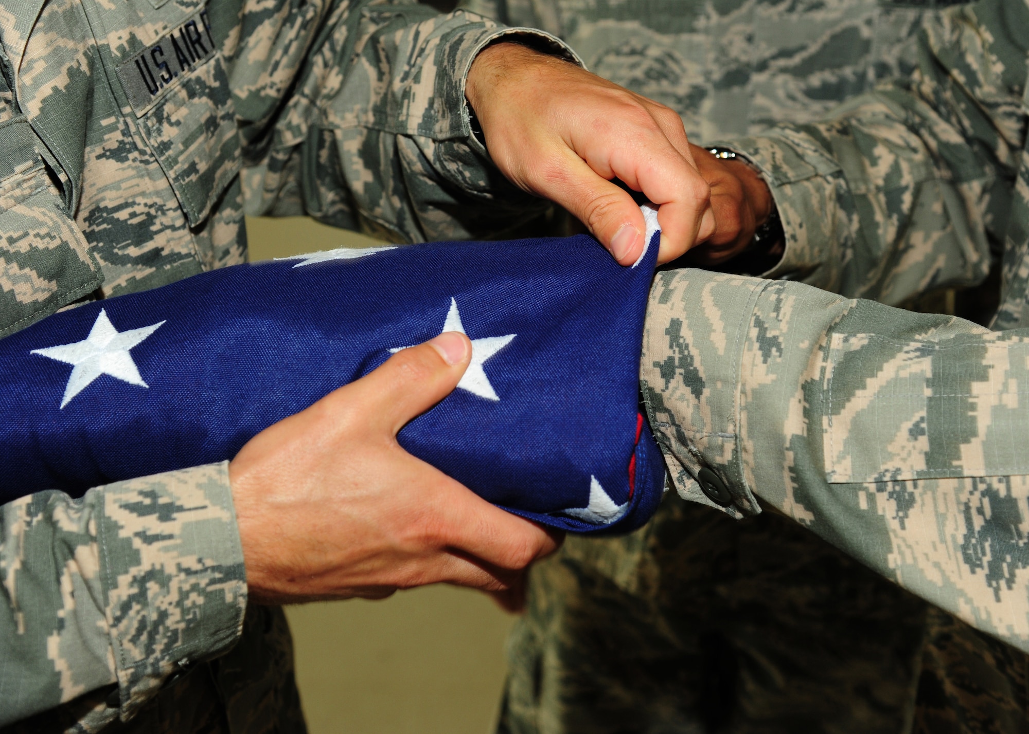 Airmen from the 319th Air Base Wing practice folding the flag before a formal retreat ceremony August 19, 2015, on Grand Forks Air Force Base, North Dakota. Squadrons take turns performing a formal retreat ceremony each week during the spring and summer months. (U.S. Air Force photo by Airman 1st Class Ryan Sparks/Released)