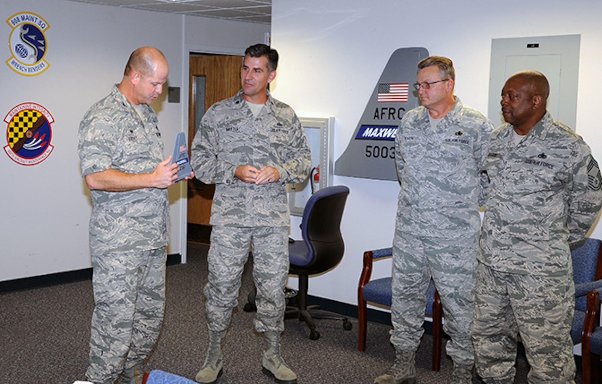 Lt. Col. James L. Hartle, deputy commander of the 908th Maintenance Group, second from left, receives a tail flash from Group Commander Col. Joe Friday while Chief Master Sgts. Douglas Dearth and Brent Hardie.