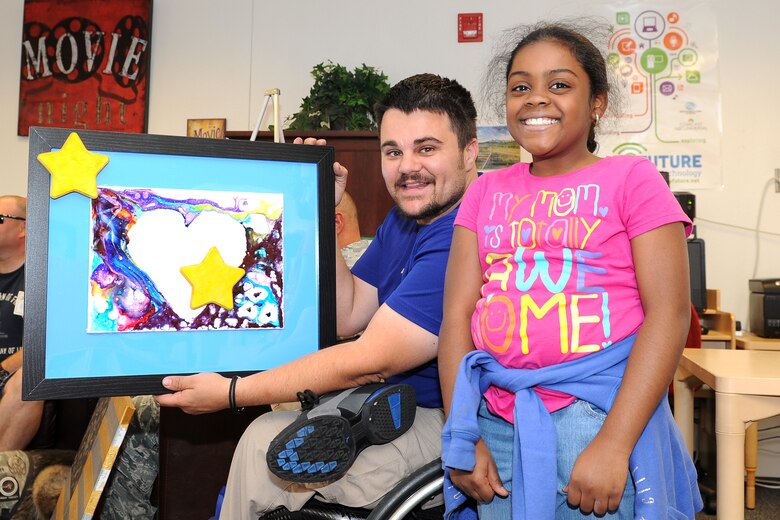 Retired Staff Sgt. Chris Wolff displays a piece of artwork presented to him by Schriever School Age Program student Ashlyn Richards during a ceremony Friday, Aug. 21, 2015 in the Schriever Child Development Center at Schriever Air Force Base, Colorado. Wolff, a member of the Air Force Wounded Warrior Program, was invited, along with three other members of the program, to the event where they were recognized for their service and sacrifice. (U.S. Air Force photo/Dennis Rogers)