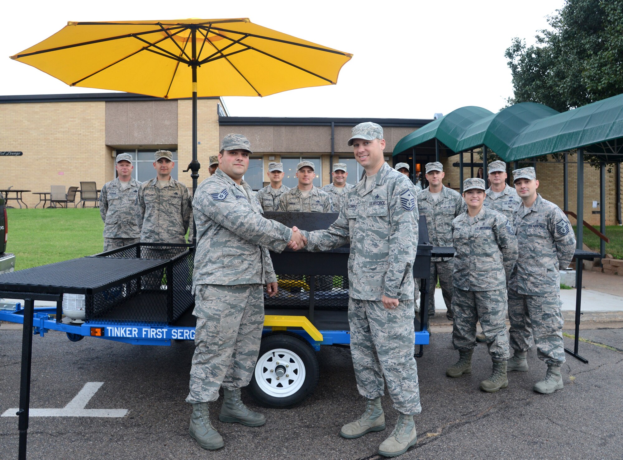 Master Sgt. Steven Colombo, Tinker First Sergeants Council president, shakes hands with Staff Sgt. Jeremy Harshbarger in recognition of his excellent work constructing the new First Sergeants grill. The new grill allows the first sergeants to be totally mobile to support all their troops for morale functions while also supplying a little class. (Air Force photo by Kelly White/Released)