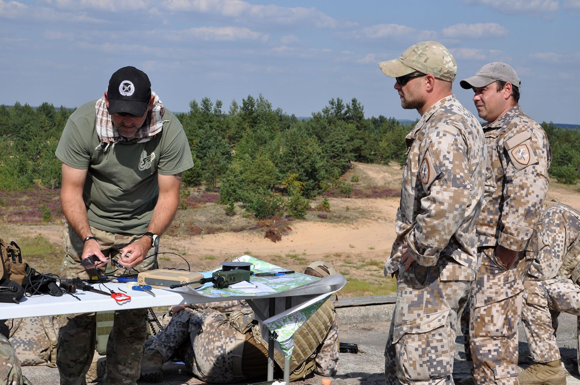 Master Sgt. Chuck Barth, a Joint Terminal Attack Controller with the Combat Readiness Training Center from Alpena, Mich., trains Sgt. Juris Salajves and Cpl. Andries Simanis, both with the Latvian military, on how to set up an antenna to establish communications during a range training exercise Aug. 24 at Adazi Range in Latvia. JTAC’s from two Air National Guard units are training with the Latvians in ground maneuvers calling for close air support using A-10 Thunderbolt IIs with the 442d Fighter Wing from Whiteman Air Force Base, Mo. U.S. forces are training with NATO allies as part of Operation Atlantic Resolve. (U.S. Air Force photo by Capt. Denise Haeussler)