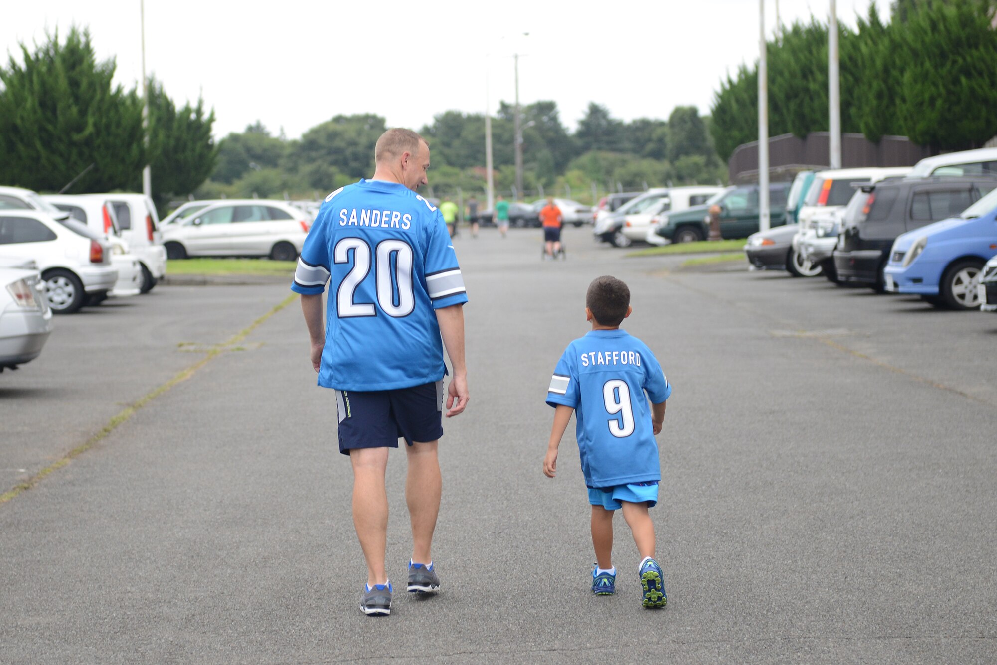 A father and son wear matching Detroit Lions football jerseys after the 'Football Frenzy 5K' at Yokota Air Base, Japan, Aug. 28, 2015. Participants wore jerseys supporting their favorite football teams as part of the event. (U.S. Air Force photo by Senior Airman David C. Danford/Released)
