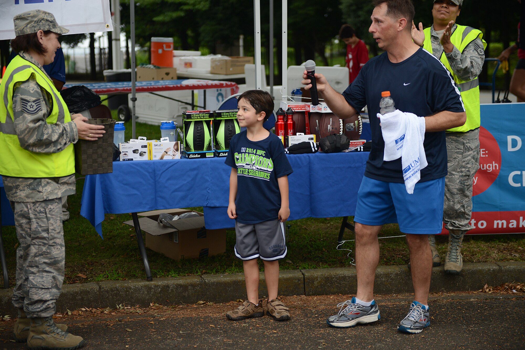 Col. Scott Maskery, 374th Mission Support Group commander, presents the first raffle prize to a child who ran the 'Football Frenzy 5K' at Yokota Air Base, Japan, Aug. 28, 2015. Prizes included footballs and water bottles. (U.S. Air Force photo by Senior Airman David C. Danford/Released)