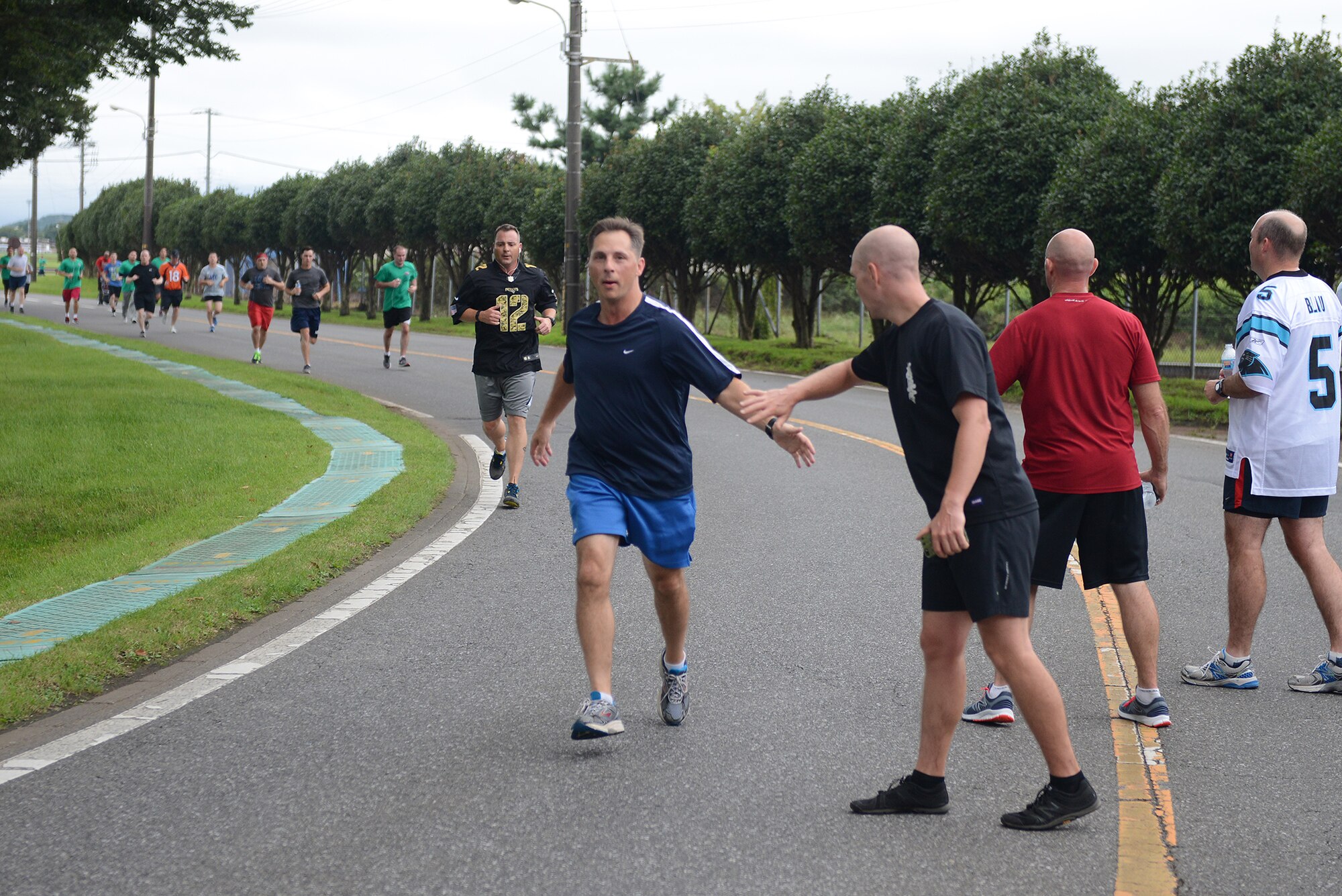 Col. Scott Maskery, 374th Mission Support Group commander, high-fives Master Sgt. Joshua Hodgin, 374th Medical Group first sergeant, as he completes the 'Football Frenzy 5K' at Yokota Air Base, Japan, Aug. 28, 2015. Participants were encouraged to wear their favorite football jersey while running. (U.S. Air Force photo by Senior Airman David C. Danford/Released)