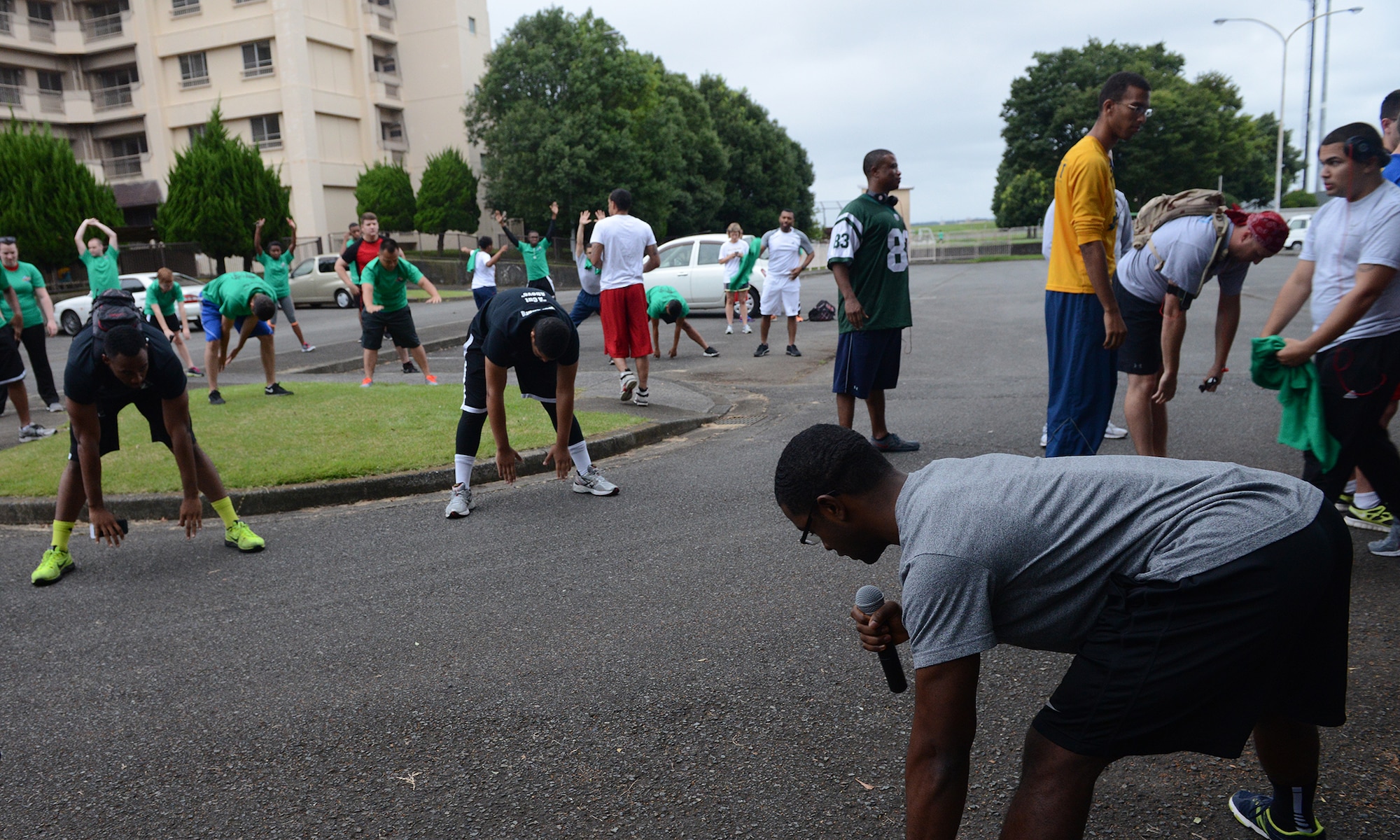 Staff Sgt. Anthony Washington, 374th Aerospace Medicine Squadron health promotion flight NCO in charge, leads stretches before the 'Football Frenzy 5K' at Yokota Air Base, Japan, Aug. 28, 2015. The warm-up stretches were held to prevent injuries and prepare the racers for the run. (U.S. Air Force photo by Senior Airman David C. Danford/Released)