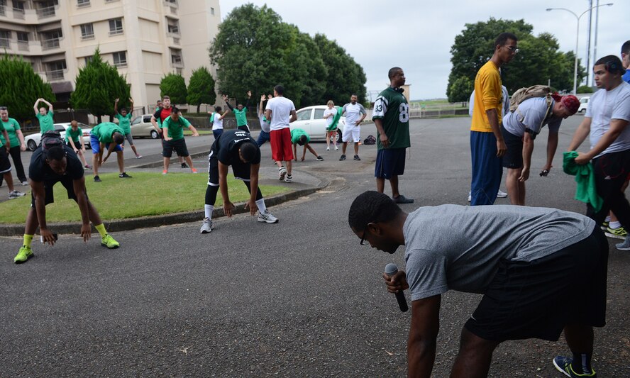 Staff Sgt. Anthony Washington, 374th Aerospace Medicine Squadron health promotion flight NCO in charge, leads stretches before the 'Football Frenzy 5K' at Yokota Air Base, Japan, Aug. 28, 2015. The warm-up stretches were held to prevent injuries and prepare the racers for the run. (U.S. Air Force photo by Senior Airman David C. Danford/Released)