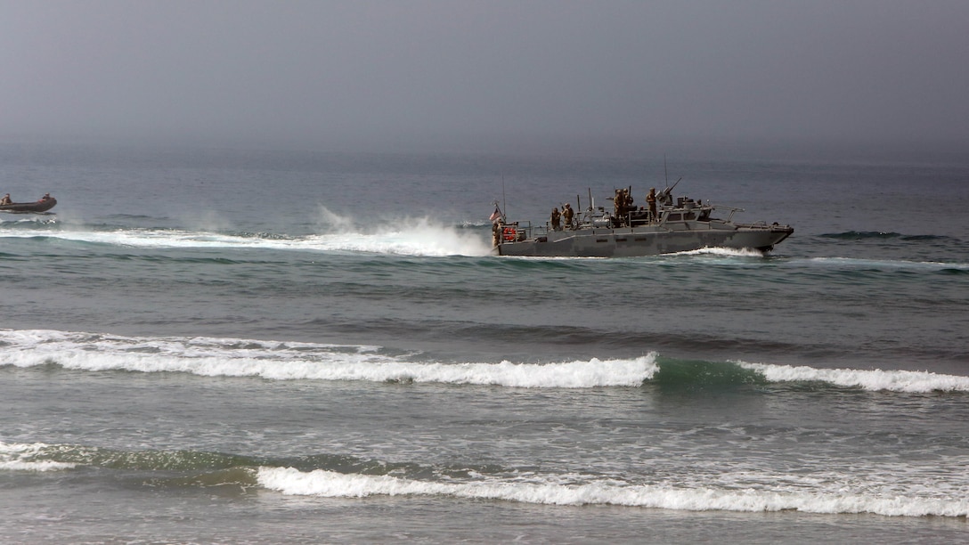 Marines with 1st Reconnaissance Battalion, 1st Marine Division, prepare to jump off a riverine command boat and swim ashore during an amphibious raid demonstration in conjunction with a visit from the secretary of defense, aboard Marine Corps Base Camp Pendleton, Calif., Aug. 27, 2015.  The Marines inserted close to the beach and swam ashore to conduct a beach reconnaissance with the mission to identify any obstacles or enemy that may interfere with the main amphibious landing. 