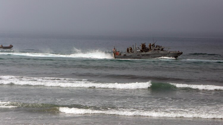 Marines with 1st Reconnaissance Battalion, 1st Marine Division, prepare to jump off a riverine command boat and swim ashore during an amphibious raid demonstration in conjunction with a visit from the secretary of defense, aboard Marine Corps Base Camp Pendleton, Calif., Aug. 27, 2015.  The Marines inserted close to the beach and swam ashore to conduct a beach reconnaissance with the mission to identify any obstacles or enemy that may interfere with the main amphibious landing. 