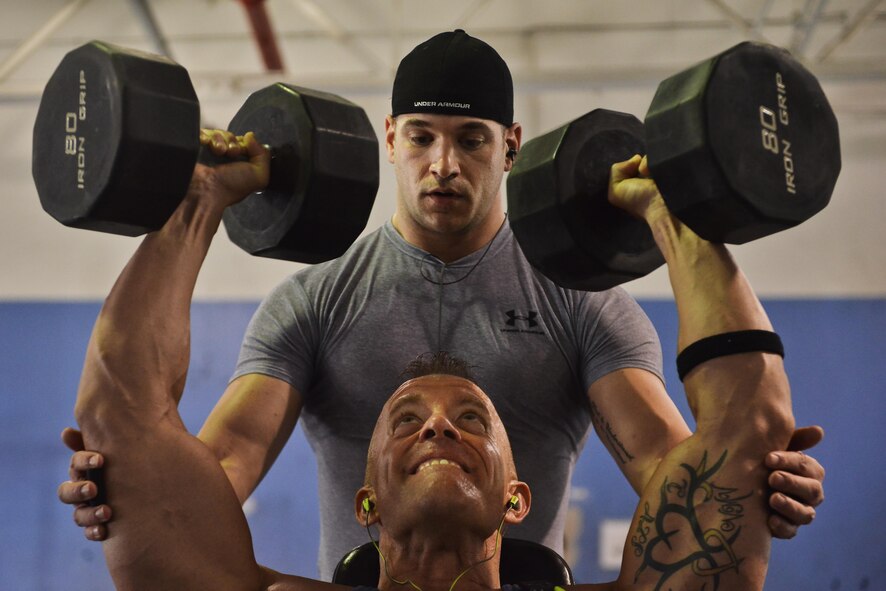 Maj. Keith Vanderhoeven, Air Force Central Command Combined Air Operations Center director of lessons learned, pushes to complete one more repetition of dumbbell shoulder presses August 23, 2015 Al Udeid Air Base, Qatar. (U.S. Air Force photo/Staff Sgt. Alexandre Montes)