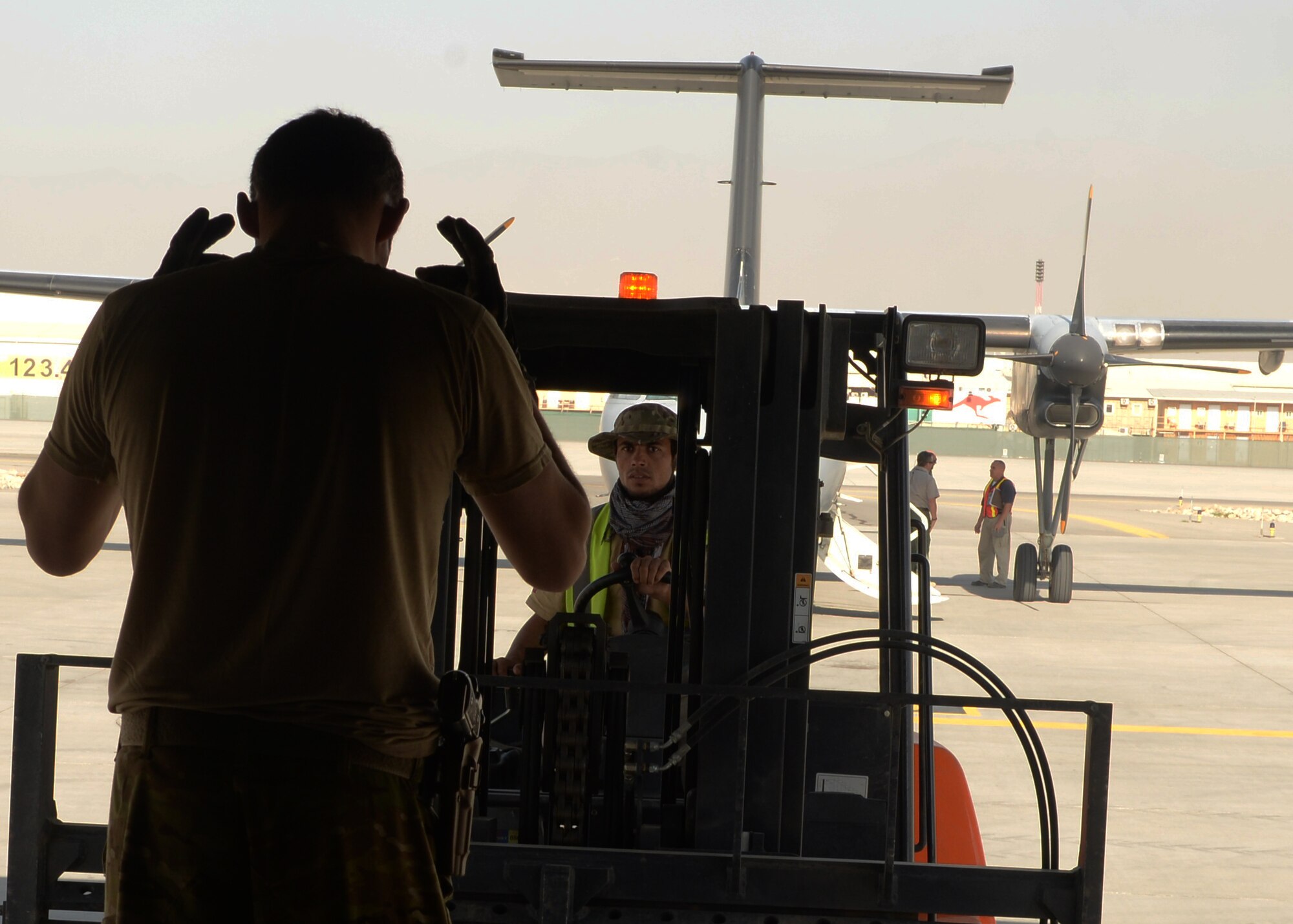 U.S. Air Force Staff Sgt. Casey Strauss, 774th Expeditionary Airlift Squadron C-130J Super Hercules aircraft loadmaster, directs a cargo loader during a shipment pick-up Aug. 28, 2015, at Hamid Karzai International Airport in Kabul, Afghanistan. Strauss and his fellow loadmasters are responsible for loading and unloading cargo, passenger safety in flight, and ensuring the aircraft stays within the proper weight and balance limitations. (U.S. Air Force photo by Senior Airman Cierra Presentado/Released)