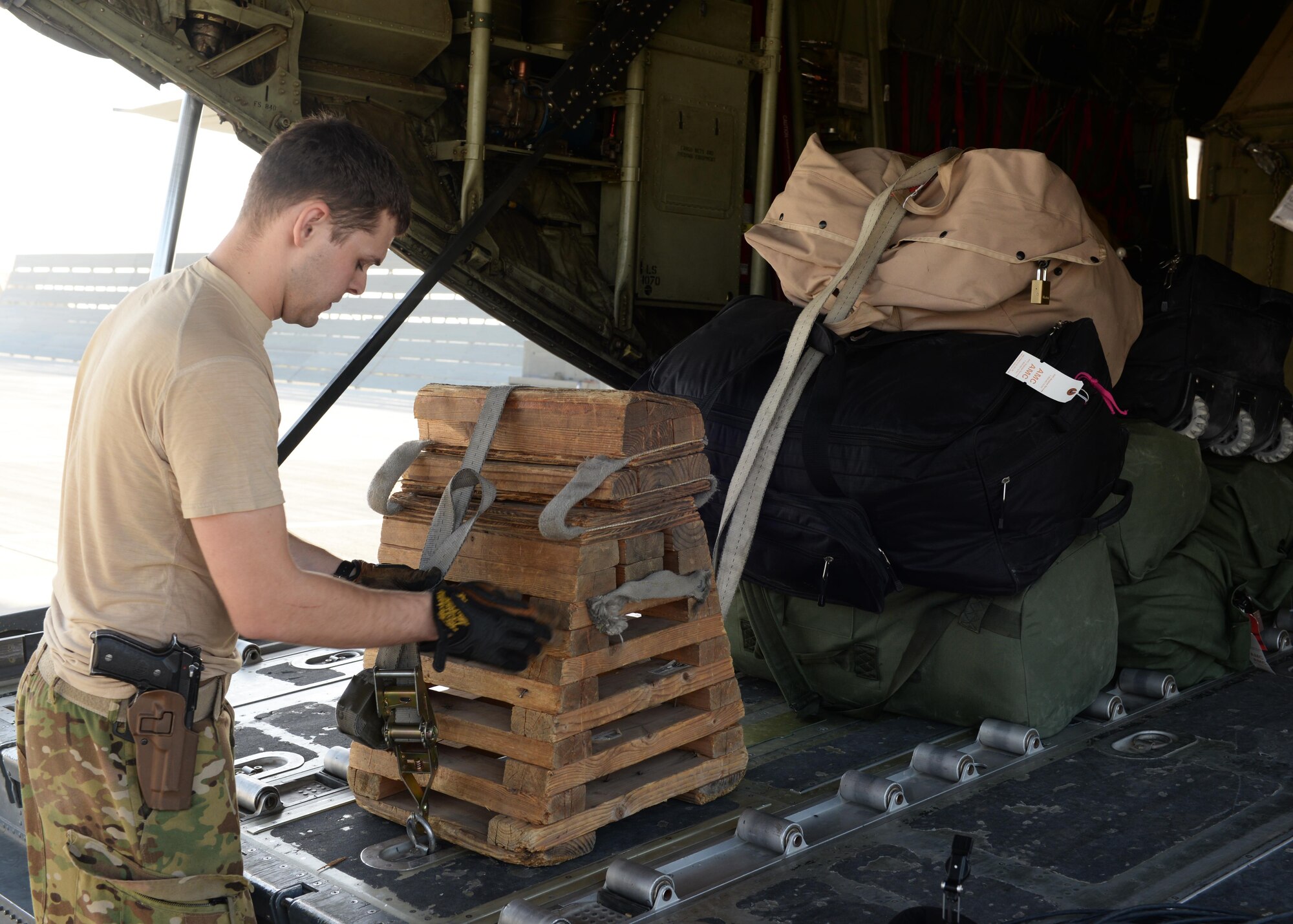 U.S. Air Force Staff Sgt. Casey Strauss, 774th Expeditionary Airlift Squadron C-130J Super Hercules aircraft loadmaster secures cargo onto an aircraft before takeoff Aug. 28, 2015 at Bagram Airfield, Afghanistan. Strauss and his fellow loadmasters are responsible for loading and unloading cargo, passenger safety in flight, and ensuring the aircraft stays within the proper weight and balance limitations. (U.S. Air Force photo by Senior Airman Cierra Presentado/Released)