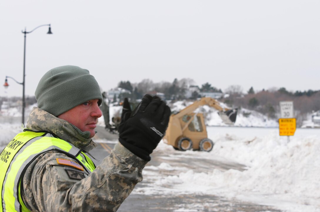 Massachusetts Army National Guard Staff Sgt. Michael Petterson directs traffic during snow removal on Ocean Avenue in Marblehead, Mass., Feb. 21, 2015. Petterson is assigned to the 972nd Military Police Company, which was tasked with assisting police while local communities recovered from unprecedented winter storms. Massachusetts Army National Guard photo by Spc. Kyleen Kelleher