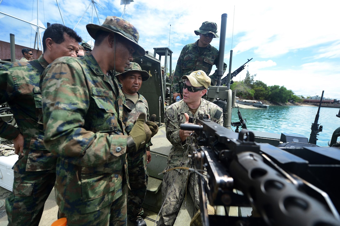 U.S. Navy Petty Officer 2nd Class Andrew Baldwin demonstrates firing a .50-caliber machine gun to members of the Thai navy's Riverine Patrol Regiment during Cooperation Afloat Readiness and Training Thailand 2015 in Sattahip, Thailand, Aug. 27, 2015. In its 21st year, the exercise includes the U.S. Navy, U.S. Marine Corps and the armed forces of nine partner nations. U.S. Navy photo by Petty Officer 1st Class Joshua Scott