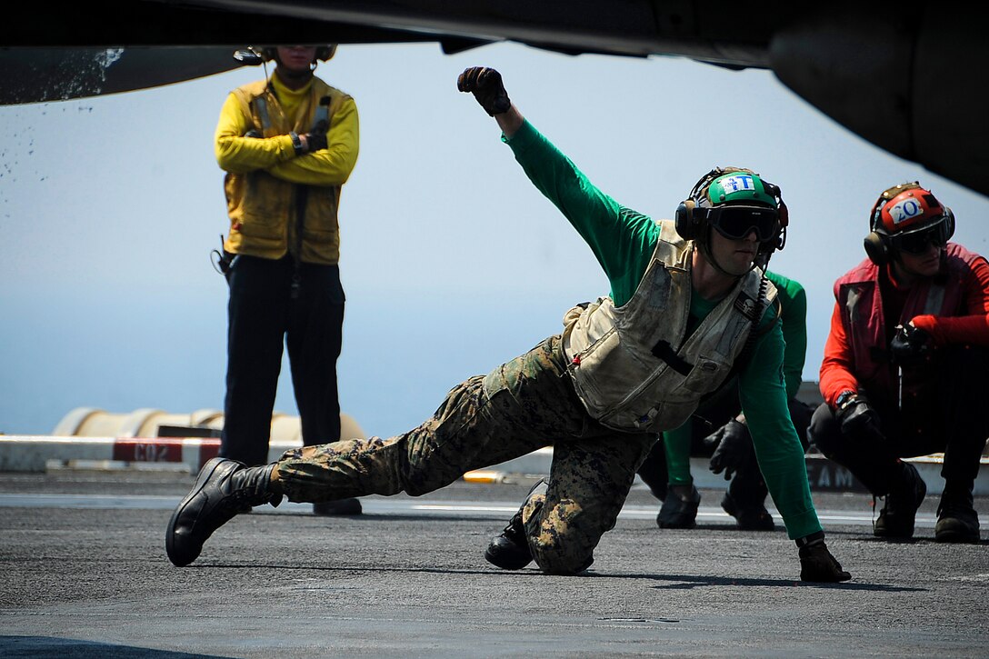 A U.S. seaman gives the OK to launch an F/A-18C Hornet from the flight deck of the aircraft carrier USS Theodore Roosevelt in the Arabian Gulf, Aug. 27, 2015. The Hornet is assigned to Marine Strike Fighter Squadron 251. The carrier is in the U.S. 5th Fleet area of operations supporting Operation Inherent Resolve, which include strike operations in Iraq and Syria as directed. U.S. Navy photo by Petty Officer 3rd Class Anna Van Nuys