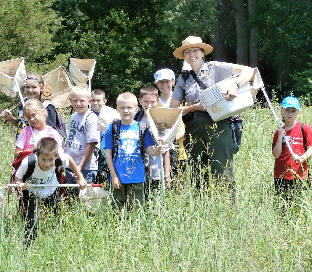 Rock Island District Park Ranger, Tracy Spry, stands with some students attending a Jr. Ranger program at Lake Red Rock in 2014.     