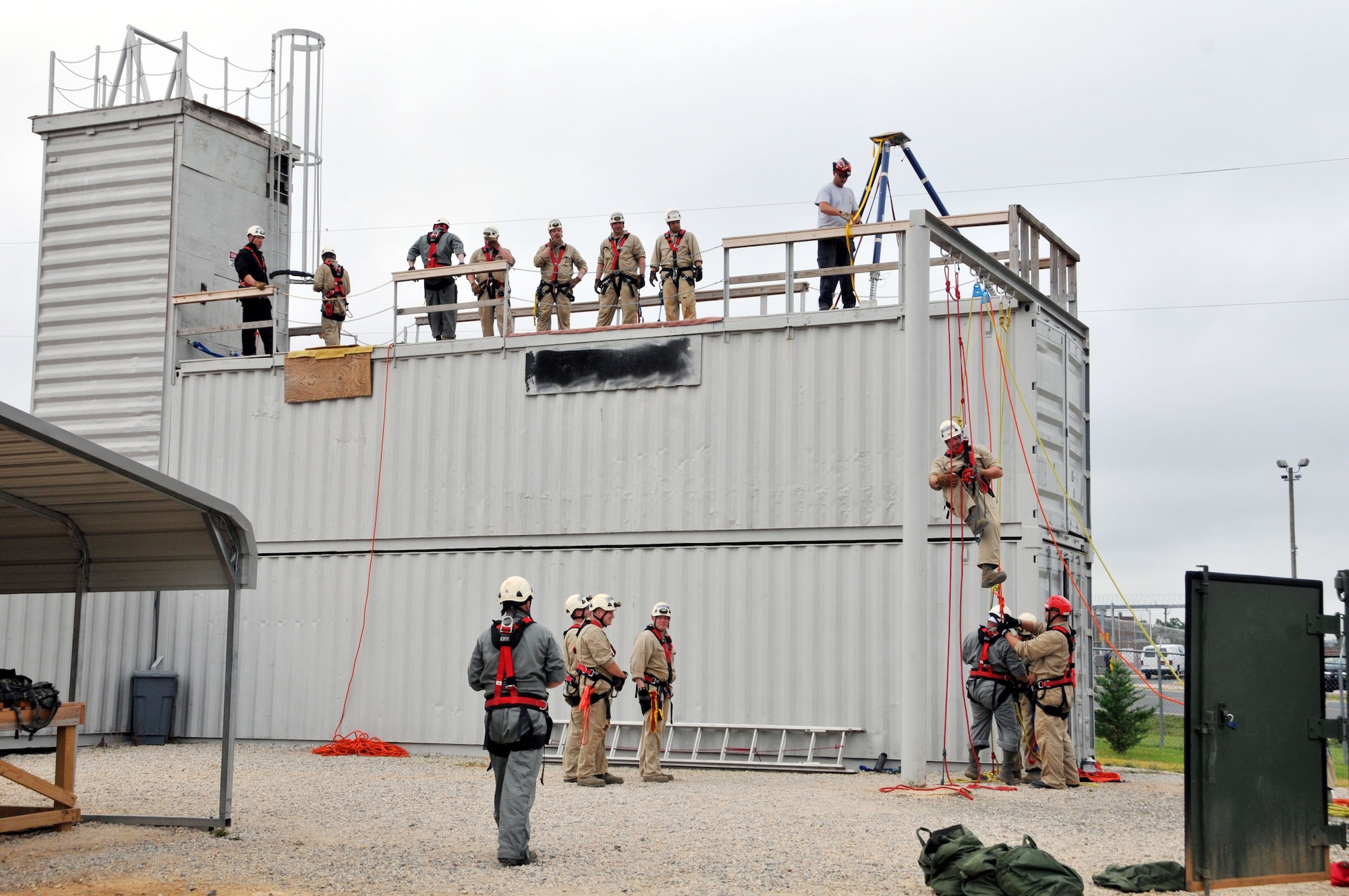 U.S. Air Force Staff Sgt. Jeret Kinnaird, firefighter for the North Carolina Air National Guard, 145th Civil Engineer Squadron, observes from rooftop as military firefighters participate in training for certification including high angle basket raising & lowering and ground ascending, descending & passing a knot at the 145th Civil Engineer Regional Training Site, New London, N.C. Kinnaird, an instructor for ANG Urban Search and Rescue Technician I and II Courses, was presented the “Chief Albert Fitzpatrick Award” for Firefighter of the Year, July 22, 2015. (U.S. Air National Guard photo by Master Sgt. Patricia F. Moran, 145th Public Affairs/Released)