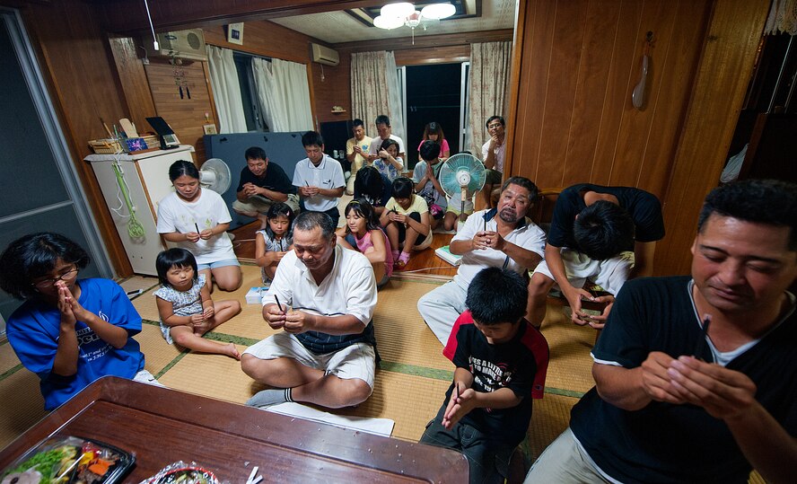 An Okinawan family gives thanks for their health and prays for their safety and happiness in front of a butsudan before sending ancestral spirits back to the other world at Yomitan village, Okinawa, Japan, Aug. 28, 2015. Okinawan families believe that during this three-day holiday deceased ancestors are allowed back from the spirit world to visit the homes of their families. (U.S. Air Force photo by Naoto Anazawa)