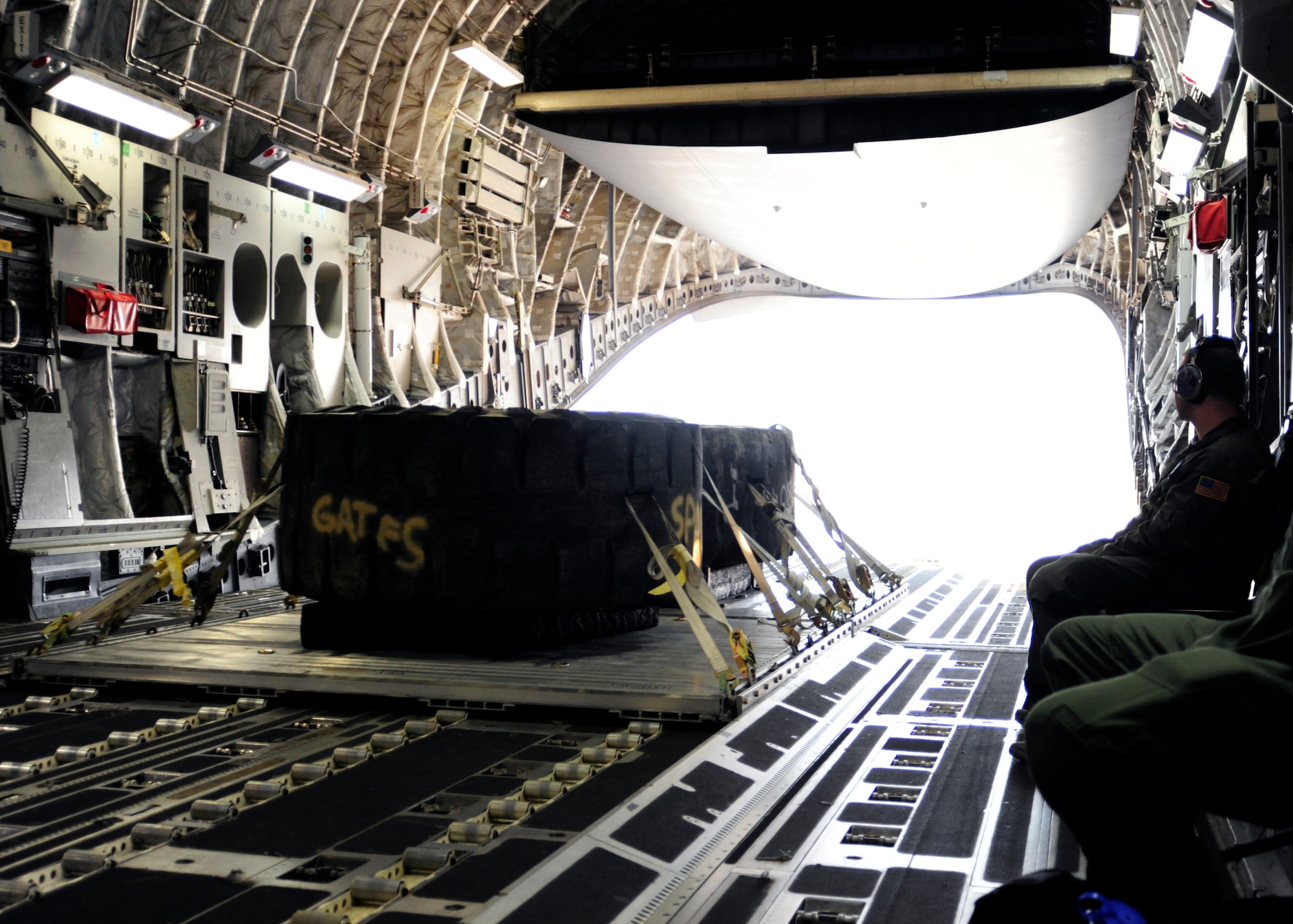 Two mock combat pallets are quickly moving on their way out of the back of a C-17 Globemaster III aircraft during a training mission at McChord Field, Aug. 12, 2015. The new pallets, using huge earth mover tires, are saving the 62nd Airlift Wing $75,000 and more than 300 man hours when all 17 pallets have been constructed. (U.S. Air Force photo/Staff Sgt. Katie Jackson)