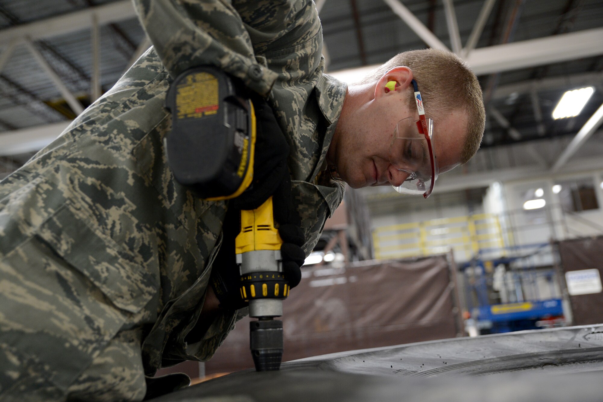 Senior Airman Jace Fore, 62nd Aerial Port Squadron ramp services element member, drills a hole into a tire July 30, 2015, at Joint Base Lewis-McChord, Wash. In an effort to create more durable pallets for combat offloads, the 62nd APS has converted wooden pallets to carry earth mover tires, which will hold up in weather and will not cause foreign object debris on the taxiway. (U.S. Air Force photo/Airman 1st Class Keoni Chavarria)