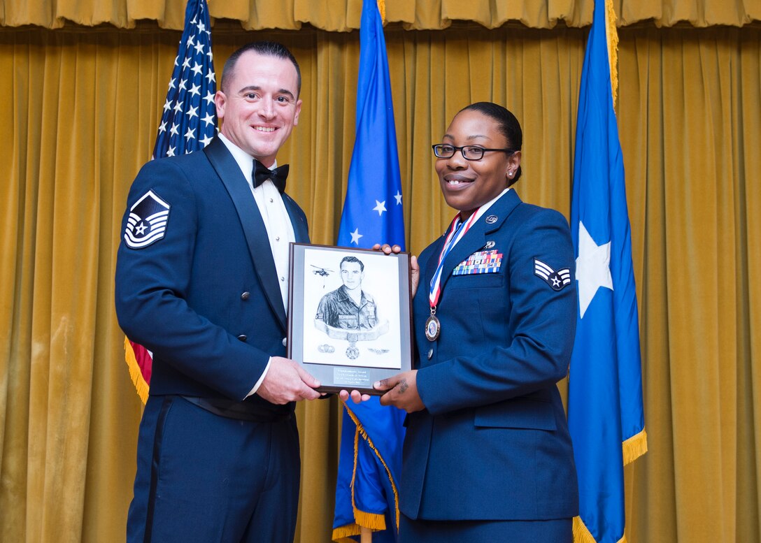 Master Sgt. Daniel Magas, Airman Leadership School commandant, hands Senior Airman Kertenisha Artison, 912th Air Refeuling Squadron (March Air Reserve Base, California), the Pitsenbarger Award, which is a peer-voted award for an outstanding Airman. (U.S. Air Force photo by Ethan Wagner)