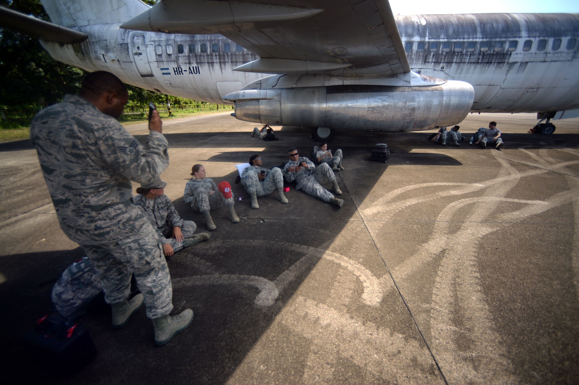 New Horizons Honduras 2015 training exercise personnel wait in the shade of an aircraft for their flight back to the United States from Base Aerea Coronel Hector Caraccioli Moncada in La Ceiba, Honduras, Aug. 28, 2015. Vehicles, equipment and personnel that were part of the New Horizons exercise redeployed to Hurlburt Field, Fla., while all remaining equipment will return via sealift. New Horizons was launched in the 1980s and is an annual joint humanitarian assistance exercise that U.S. Southern Command conducts with a partner nation in Central America, South America or the Caribbean. The exercise improves joint training readiness of U.S. and partner nation civil engineers, medical professionals and support personnel through humanitarian assistance activities. (U.S. Air Force photo by Capt. David J. Murphy/Released)