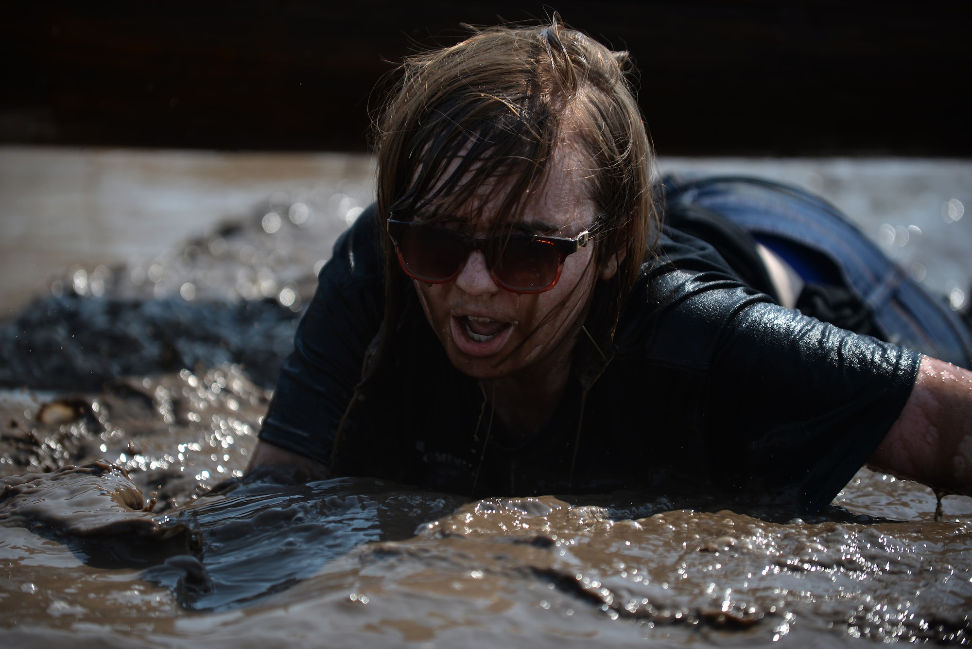 Katrina Sorrels, daughter of Maj. David Sorrels, 90th Communications Squadron commander, crawls through muddy water Aug. 29, 2015, during the second annual F.E. Warren Air Force Base, Wyo., mud run. Many families completed the course together. (U.S. Air Force photo by Airman 1st Class Brandon Valle)