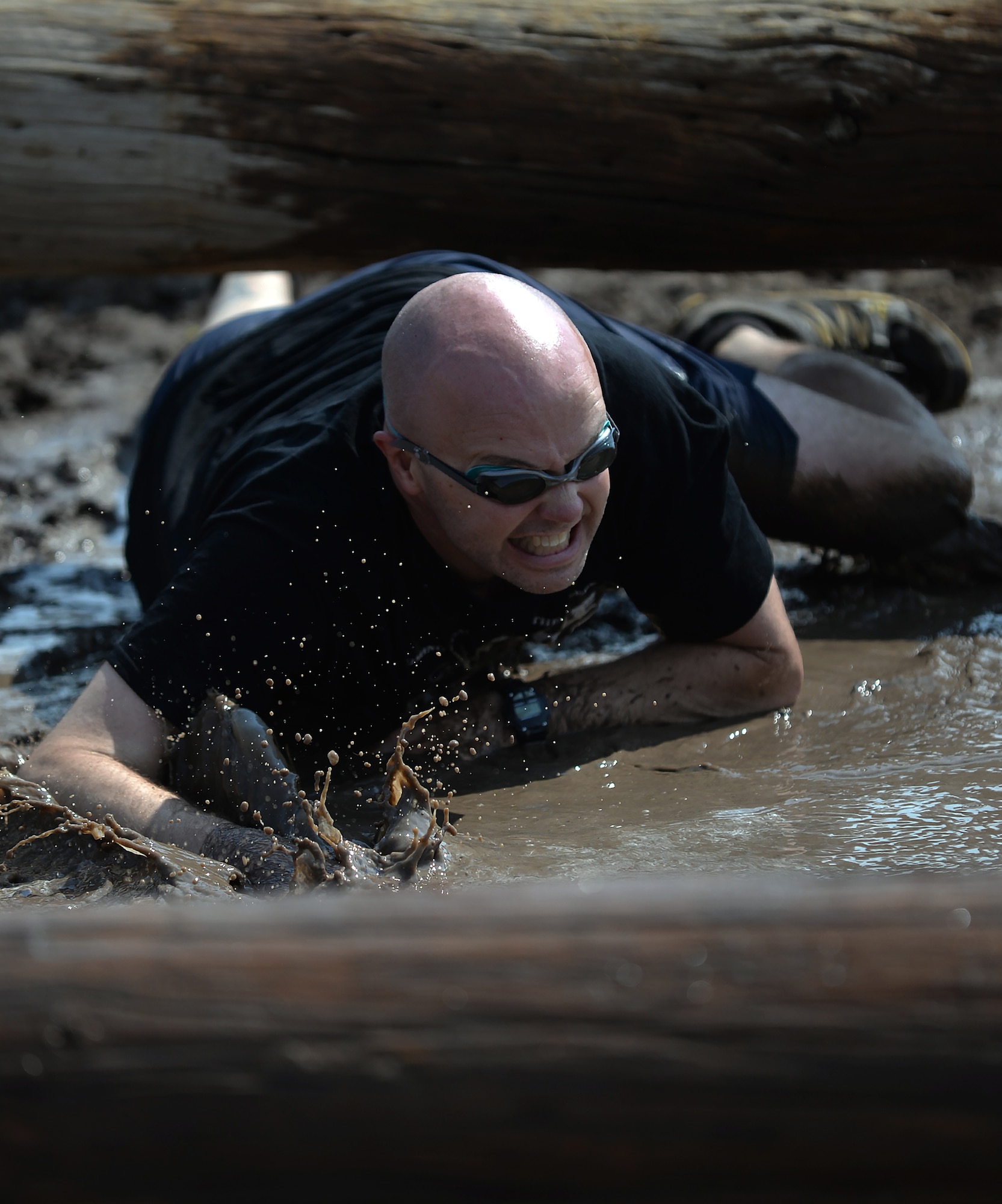 Maj. David Sorrels, 90th Communications Squadron commander, low crawls under a log through mud Aug. 29, 2015, during the second annual F.E. Warren Air Force Base, Wyo., mud run. The five-kilometer course was filled with various obstacles, with mud and water increasing the difficulty. (U.S. Air Force photo by Airman 1st Class Brandon Valle)