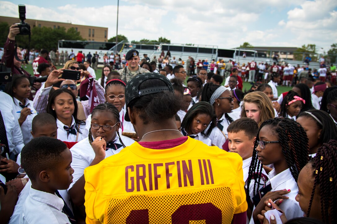 Imagine Andrews Public Charter School students swarm Washington Redskins quarterback Robert Griffin III after a Redskins walkthrough practice at the West Fitness Center’s field, Joint Base Andrews, Md., Aug. 28, 2015. The Redskins practice was followed by an autograph session with fans as part of their Redskins Salute effort. (U.S. Air Force photo by Airman 1st Class Philip Bryant/Released)