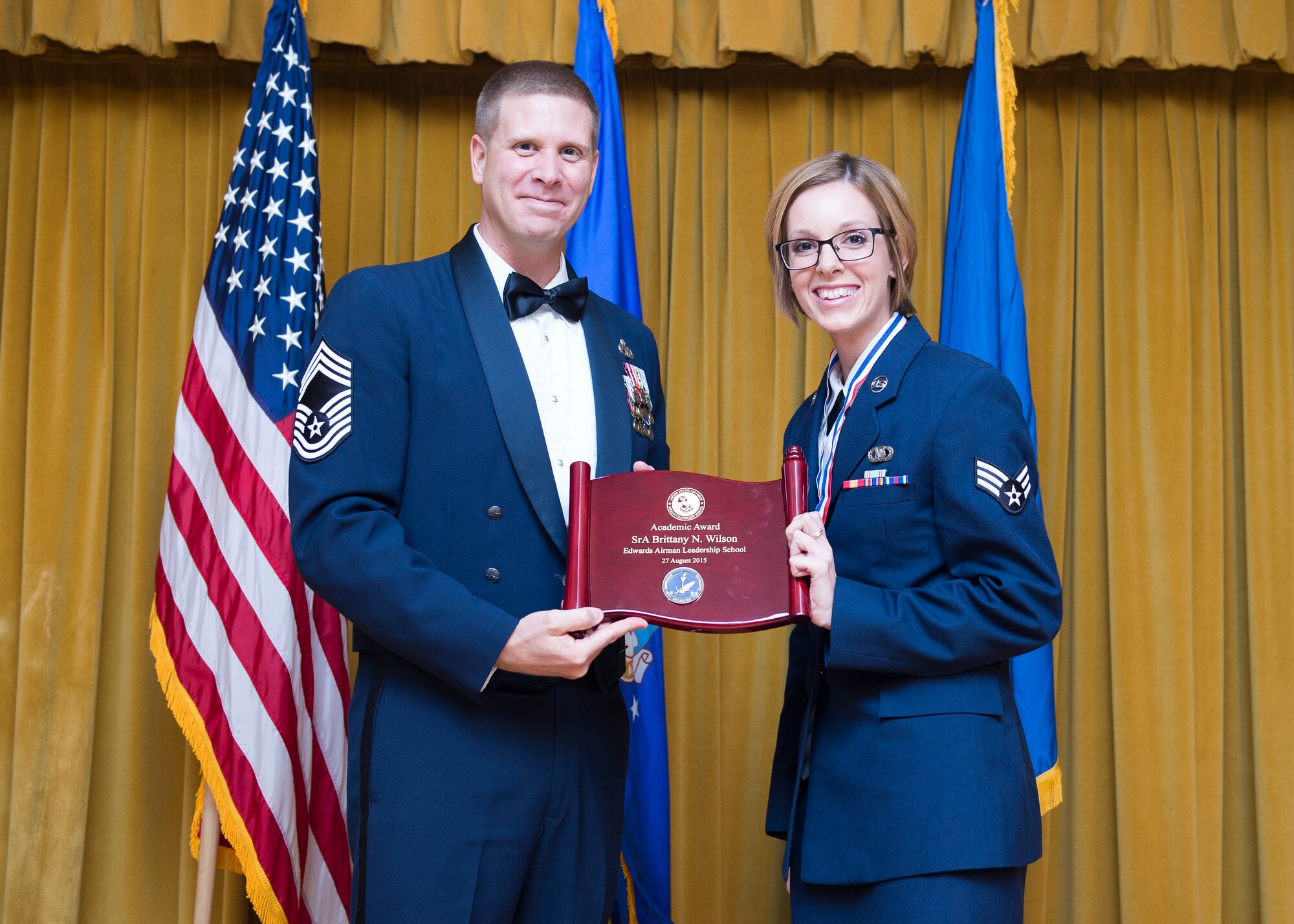 Senior Airman Brittany Wilson, U.S. Air Force Test Pilot School, received the Distinguished Graduate Award and poses for a photo with Chief Master Sgt. Kennon Arnold of the 412th Maintenance Group, who served as the keynote speaker at the Airman Leadership School Graduation held Aug. 27 at Club Muroc. (U.S. Air Force photo by Ethan Wagner)

