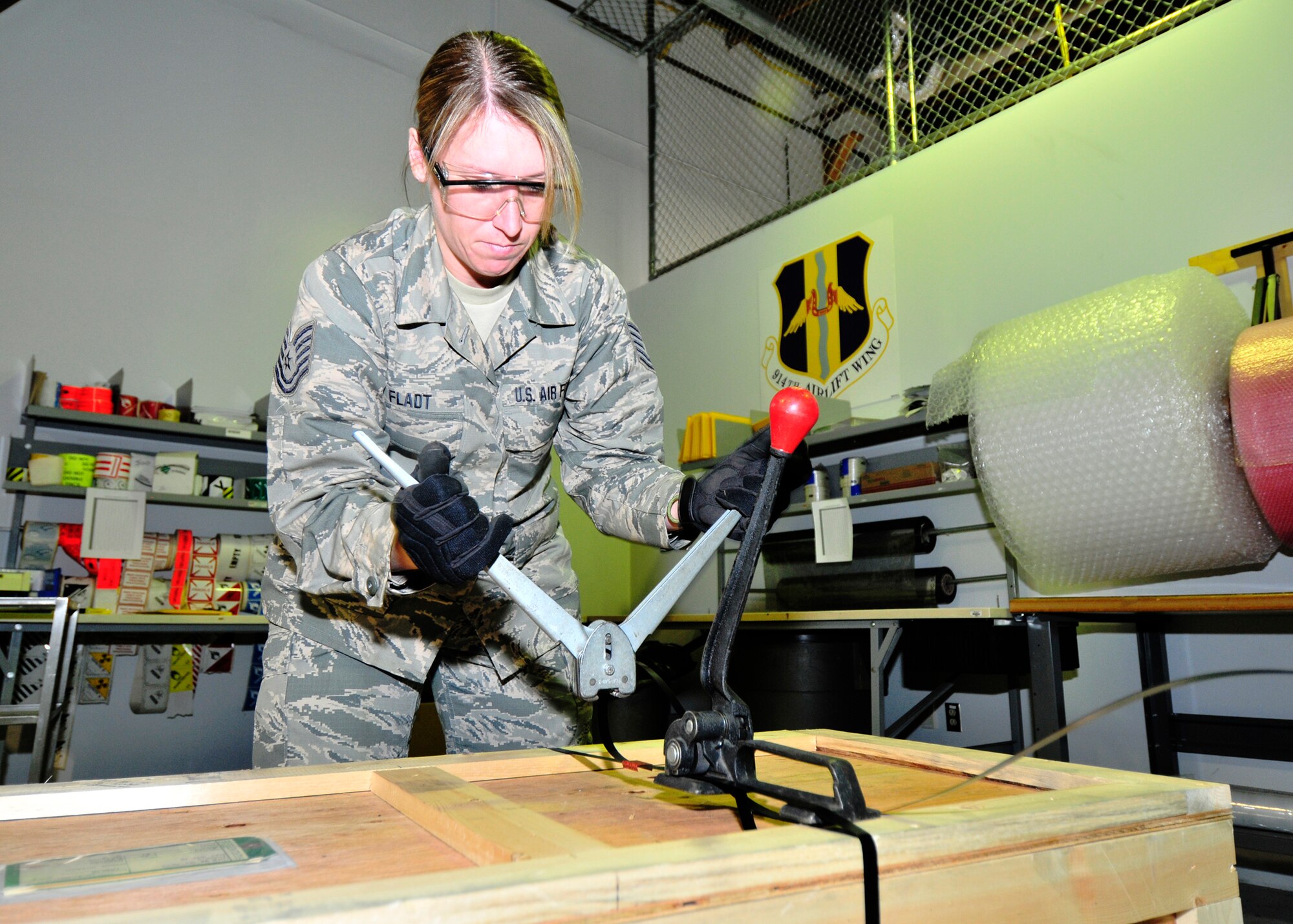 Tech. Sgt. Erika Fladt, 914th Logistics Readiness Squadron Traffic Management Craftsman bands a crate for shipment at the Niagara Falls Air Reserve Station, N.Y. on August 27, 2015. All large crates are banded to ensure the contents will remain secure during shipment. (U.S. Air Force photo by Peter Borys)
