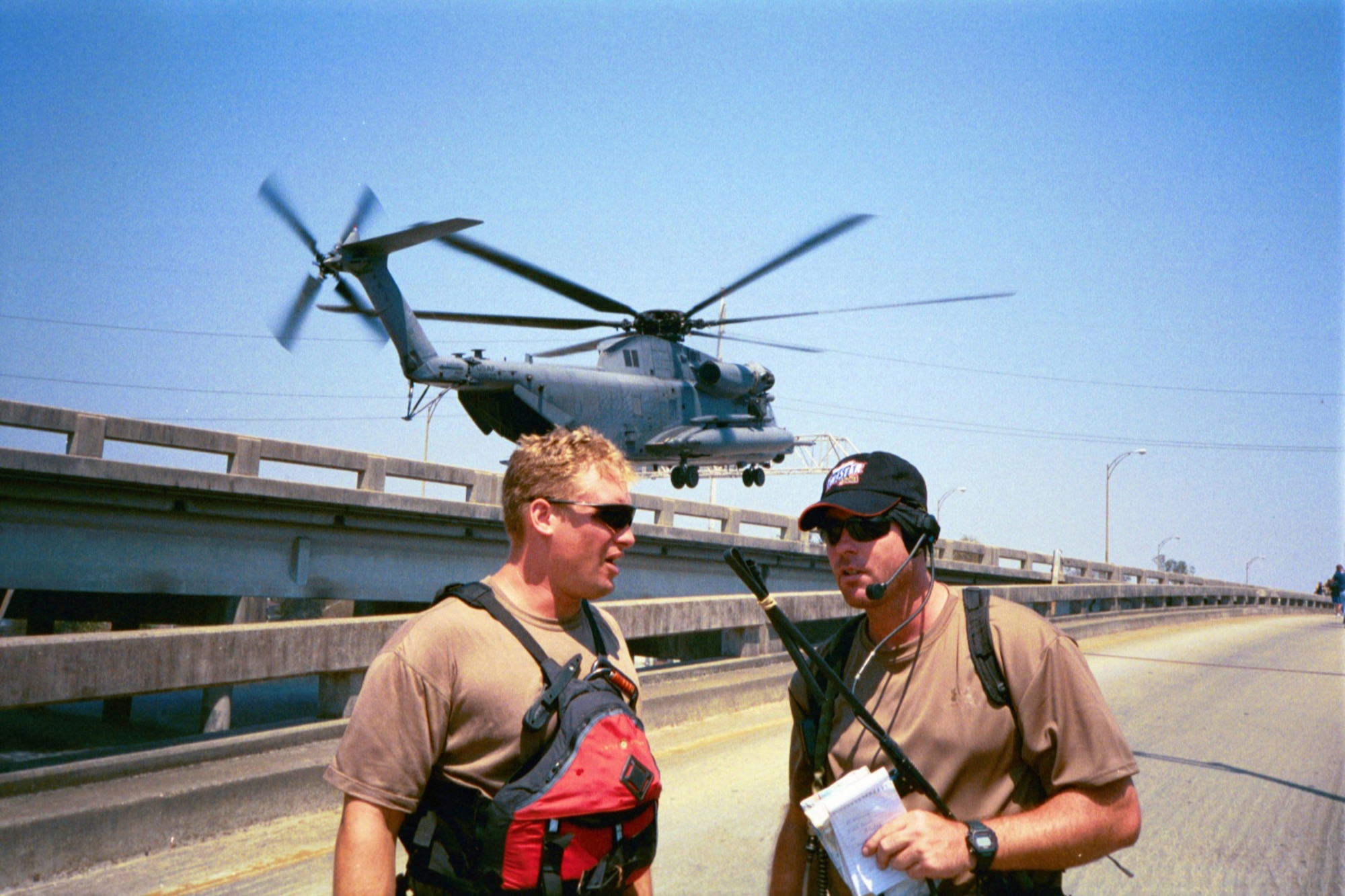 Two Kentucky Air National Guard Special Tactics troops confer as an Air Force MH-53 helicopter lands on Interstate 610 to evacuate New Orleans residents following Hurricane Katrina Sept. 4, 2005. (U.S. Air National Guard photo)