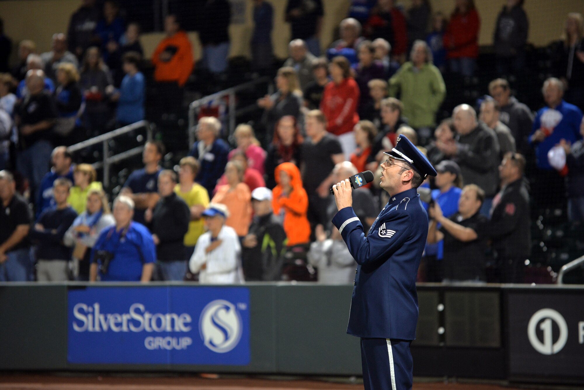 U.S. Air Force Staff Sgt. Geoffrey Fisher, Heartland of America Band vocalist, sings God Bless America during the seventh inning stretch of military appreciation night at Werner Park on Aug. 28, Papillion Nebraska.  Werner Park is home to the Omaha Storm Chasers. (U.S. Air Force photo by Josh Plueger/Released)